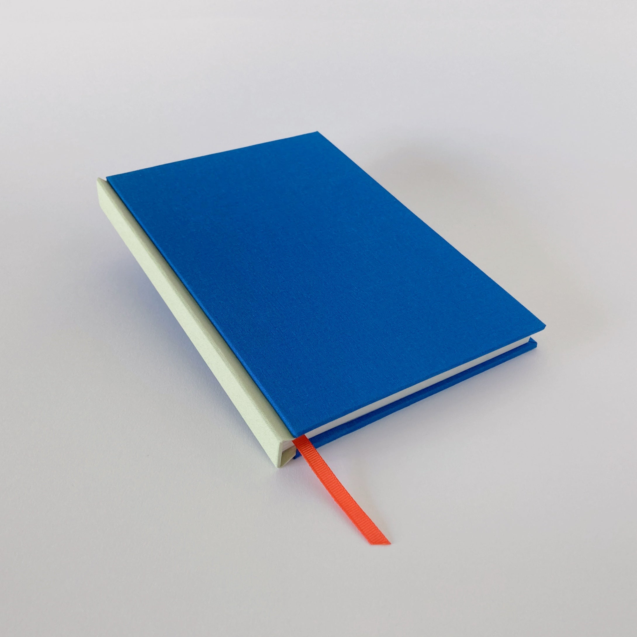 Blue clothbound sketchbook with mint spine and orange ribbon bookmark.
