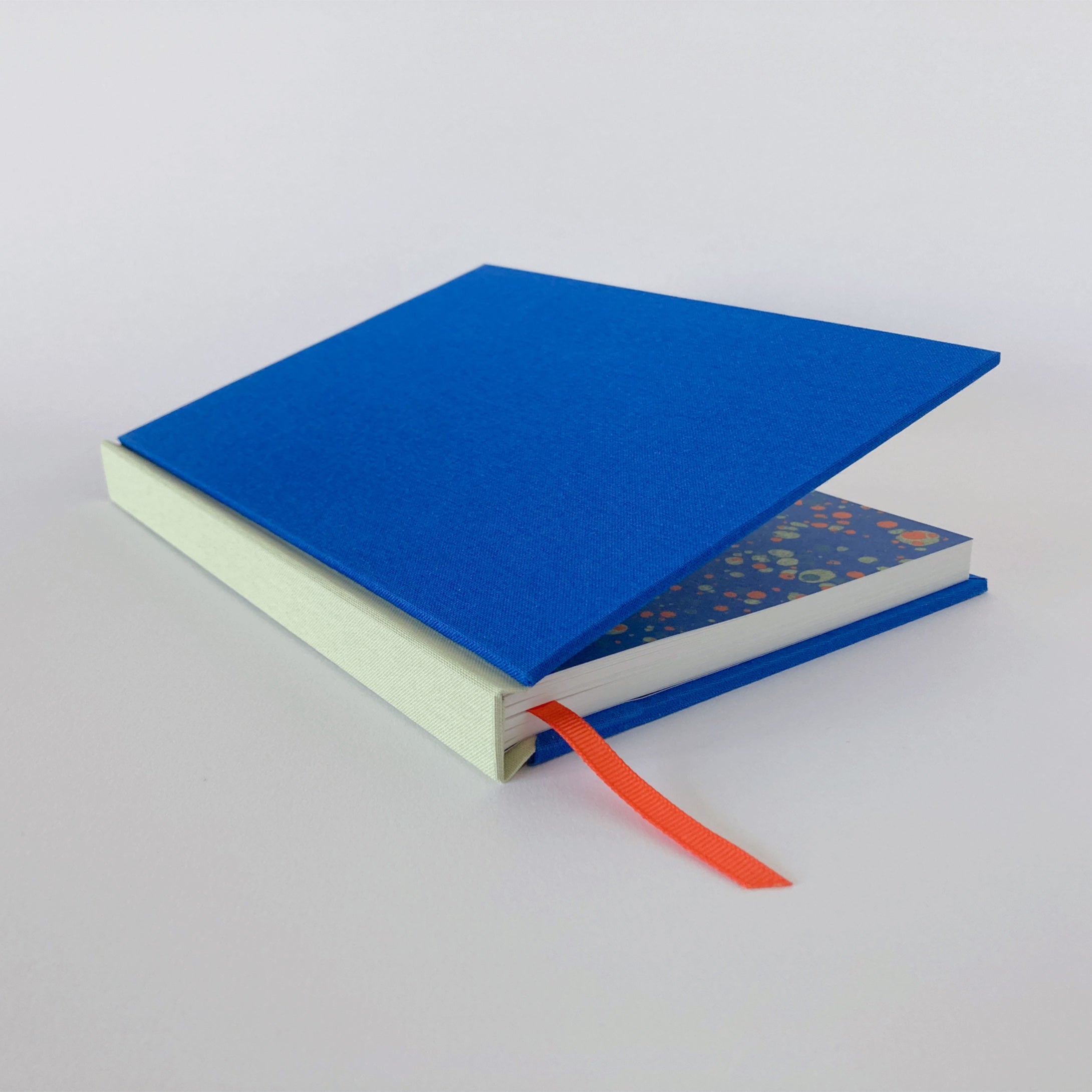 Blue and mint hardback sketchbook partially open, revealing marble endpapers.