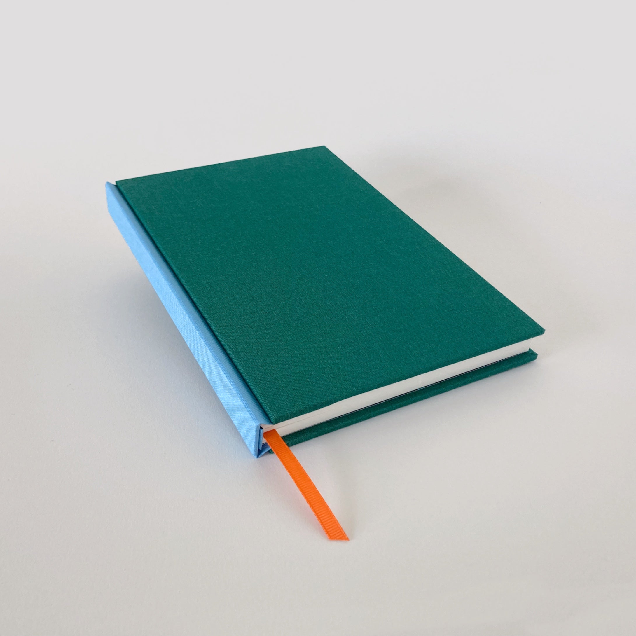 Green clothbound sketchbook with blue spine and orange ribbon bookmark.