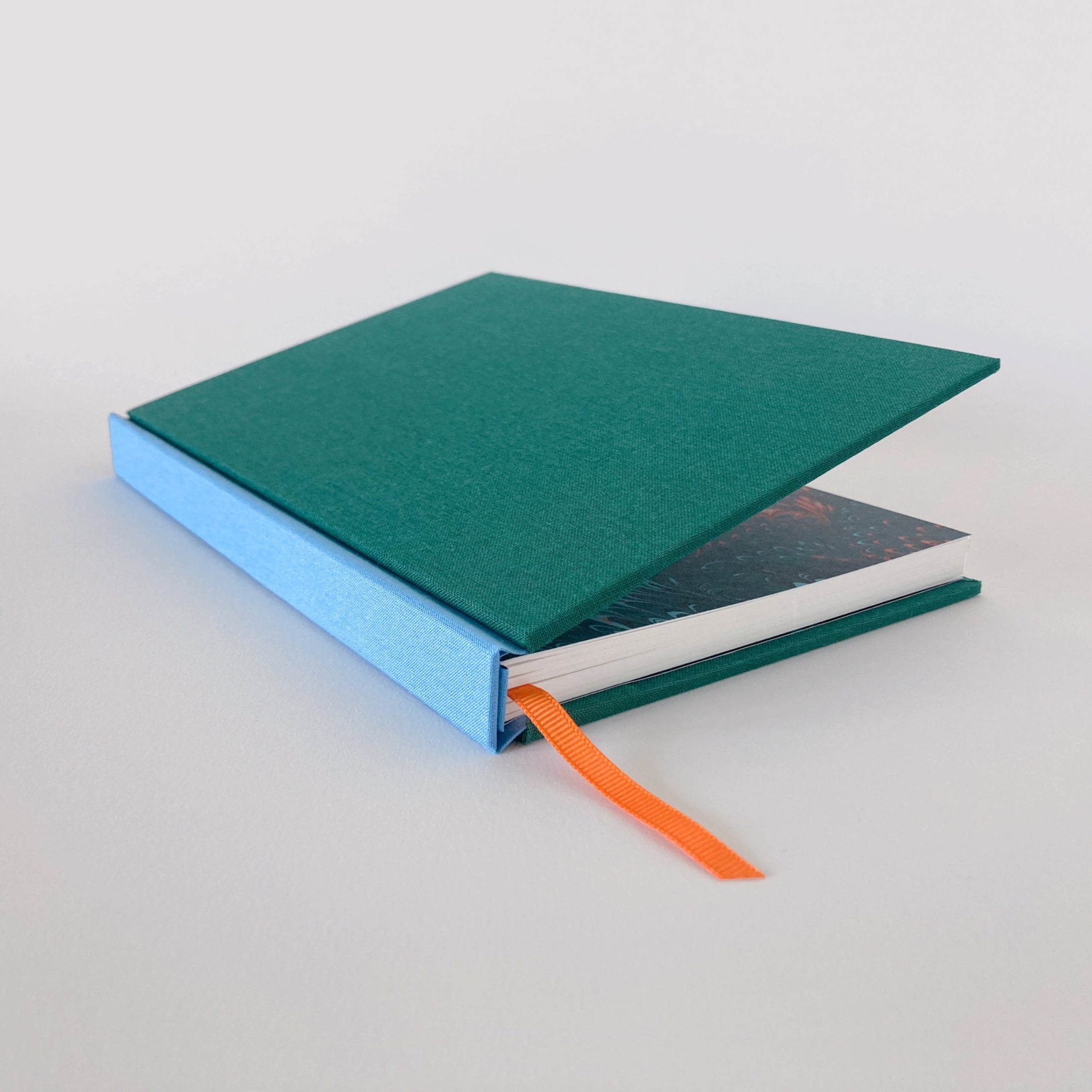 Green and blue hardback sketchbook partially open, revealing marble endpapers.