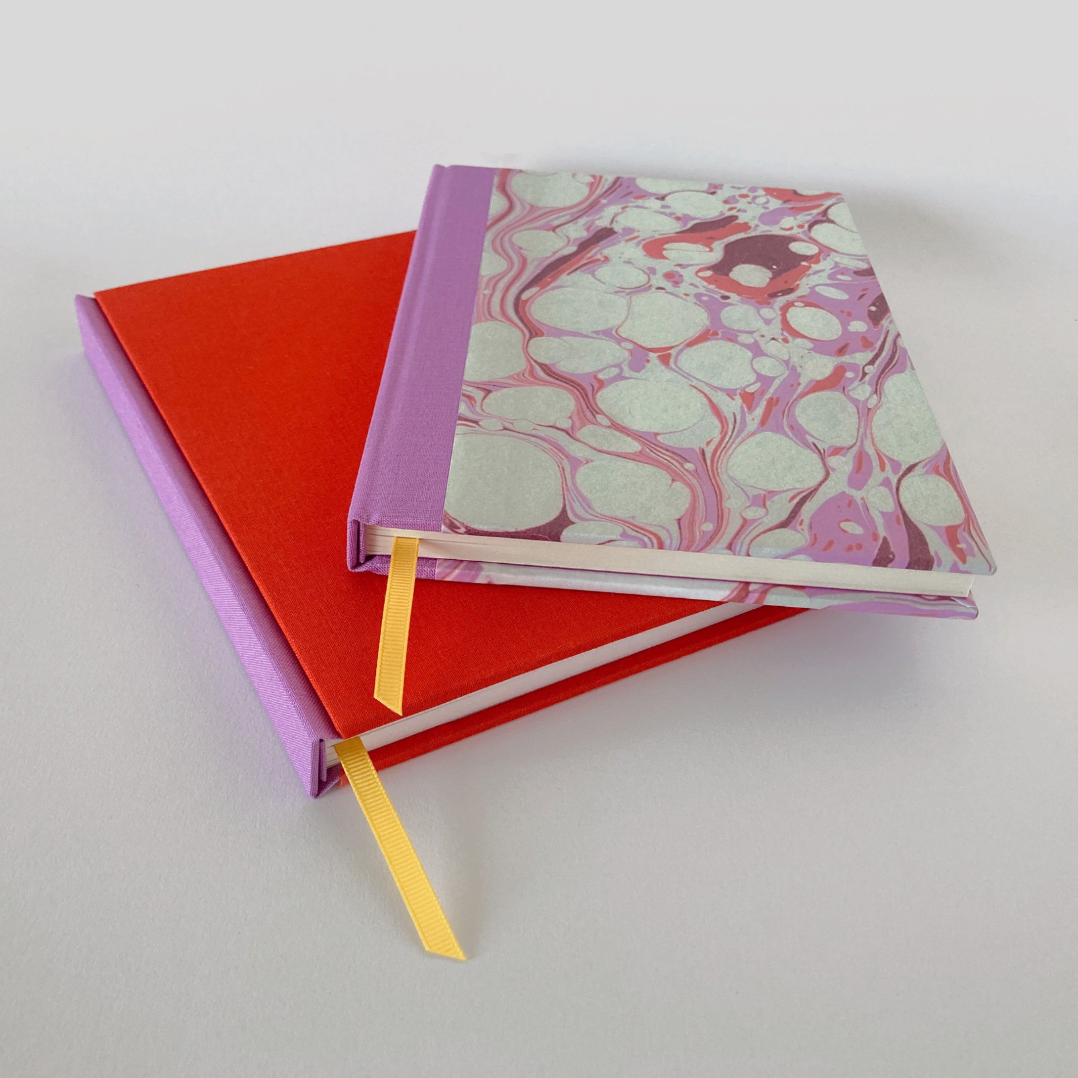 Red and pink clothbound sketchbook with pink marble notebook.