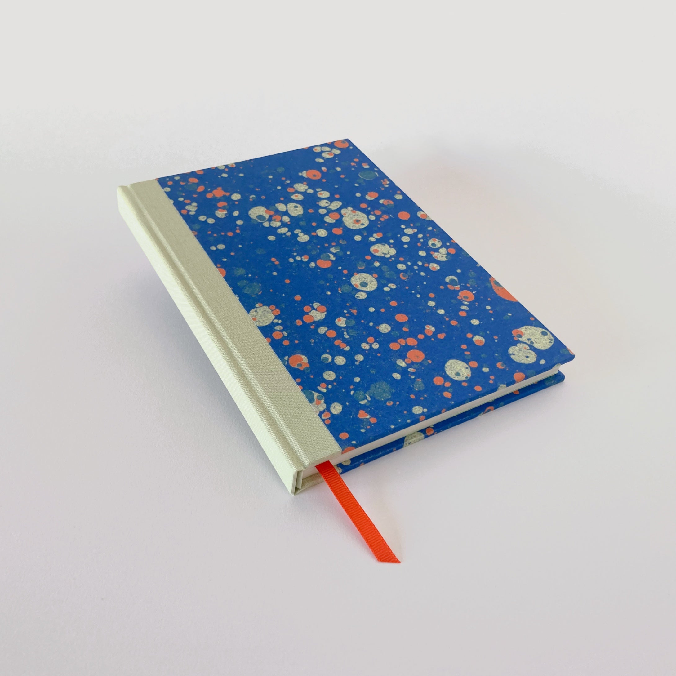 Blue marble hardback notebook with mint cloth spine and orange ribbon bookmark.
