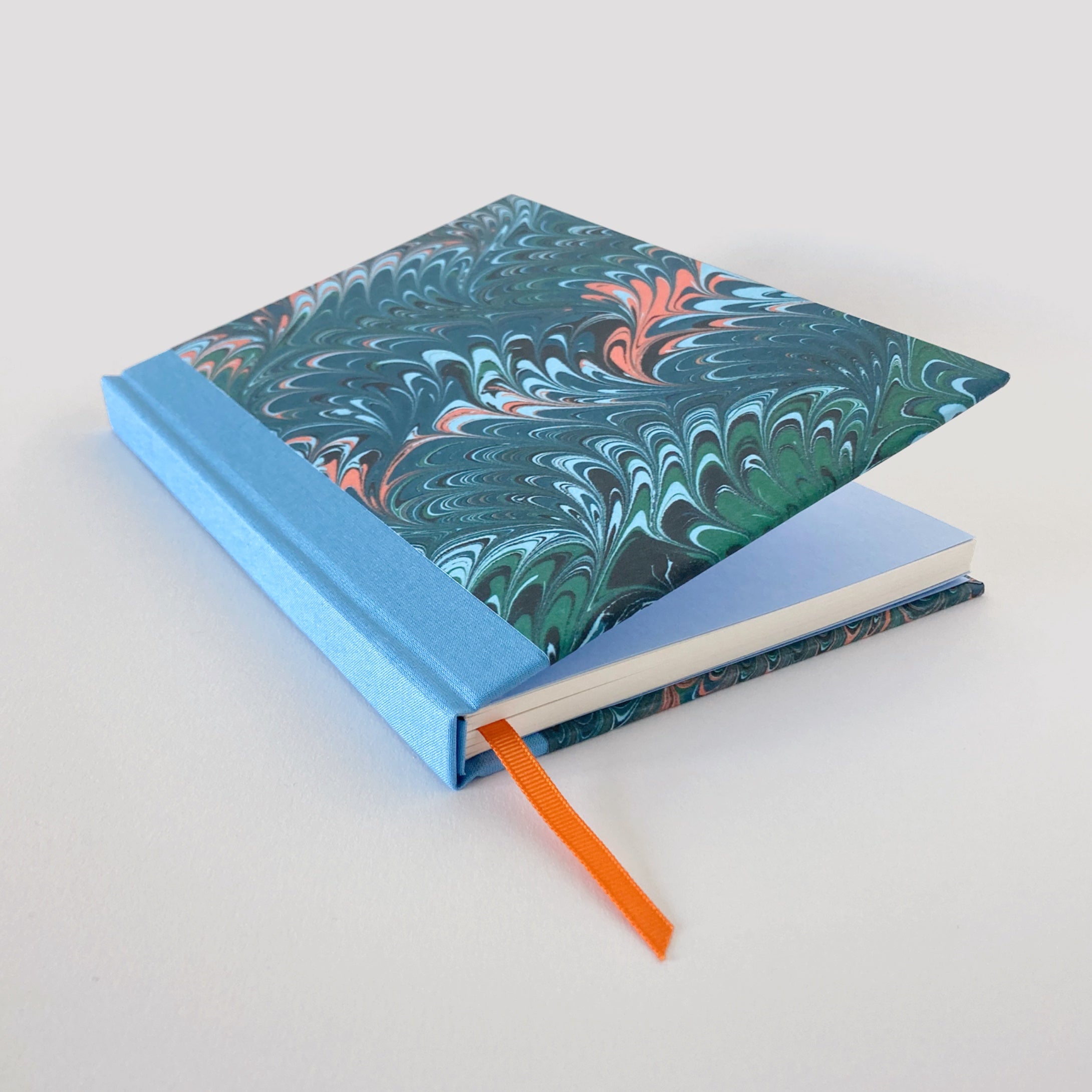 Green marble hardback notebook partially open, revealing blue end pages.