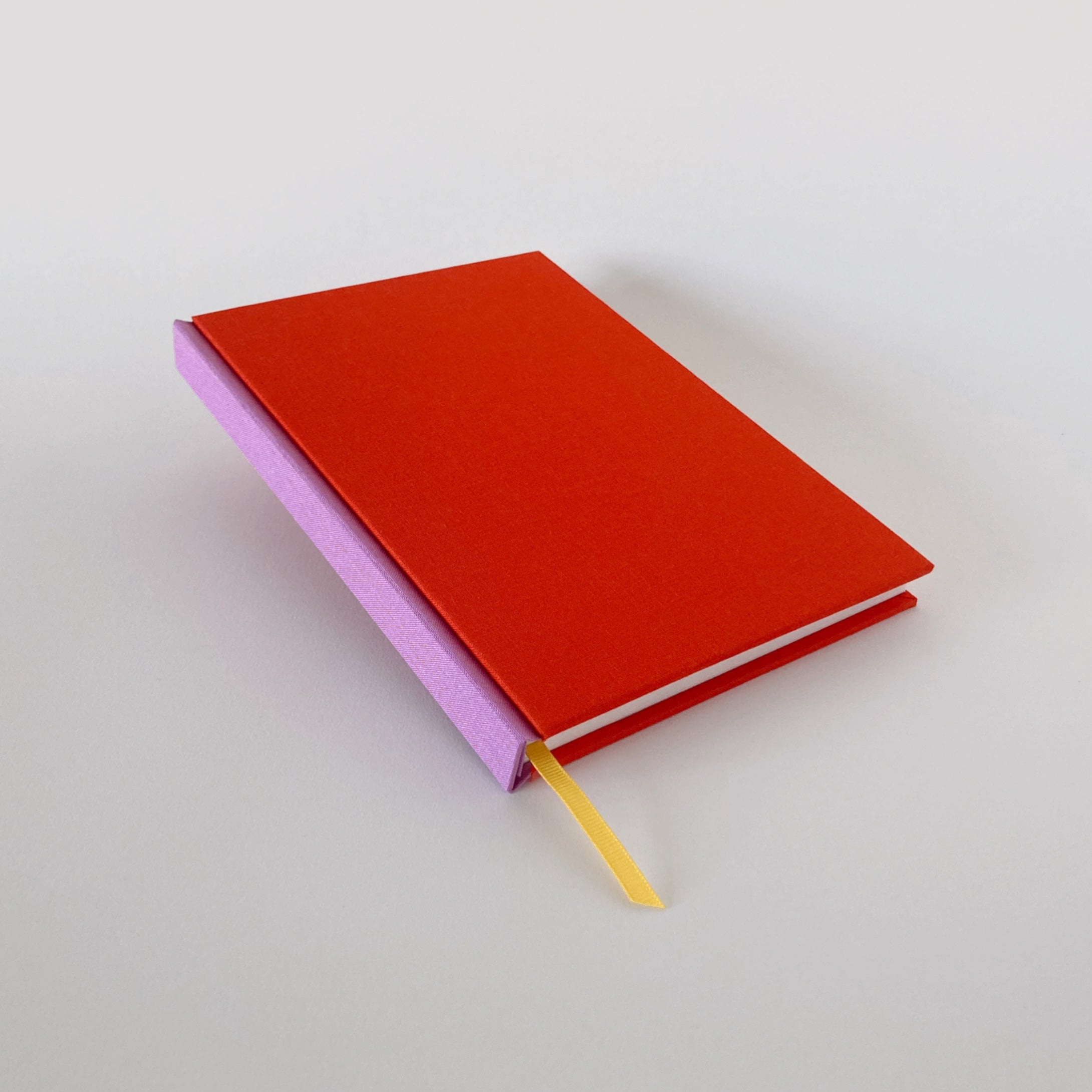 Red clothbound sketchbook with pink spine and yellow ribbon bookmark